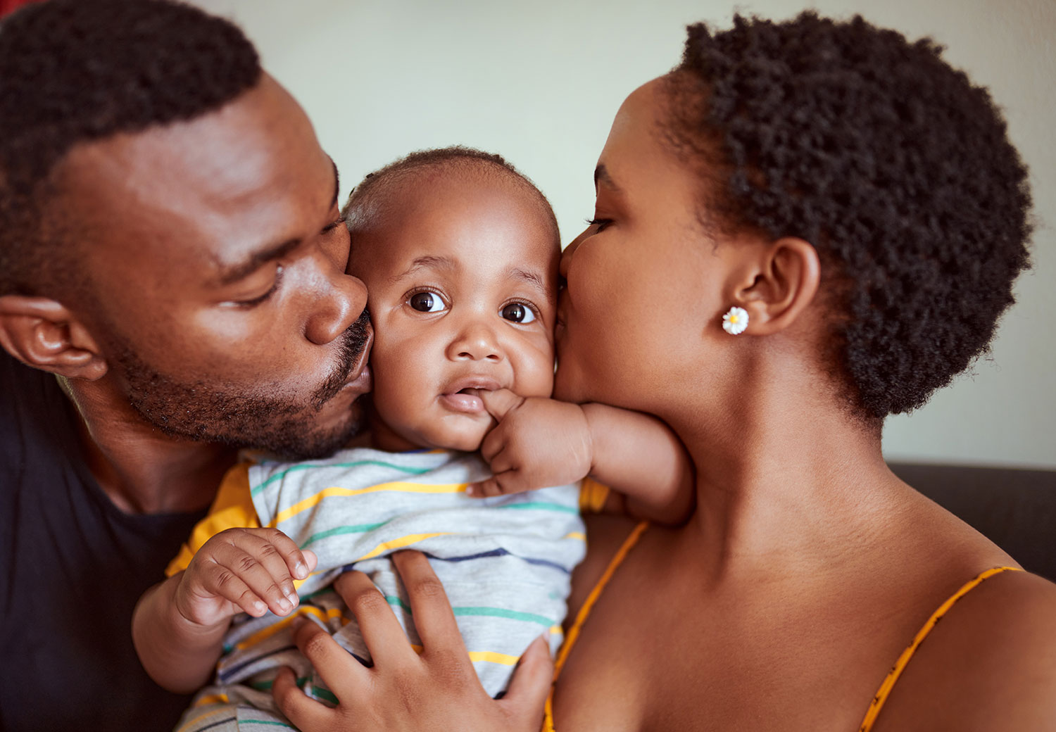African-American couple kisses their baby.